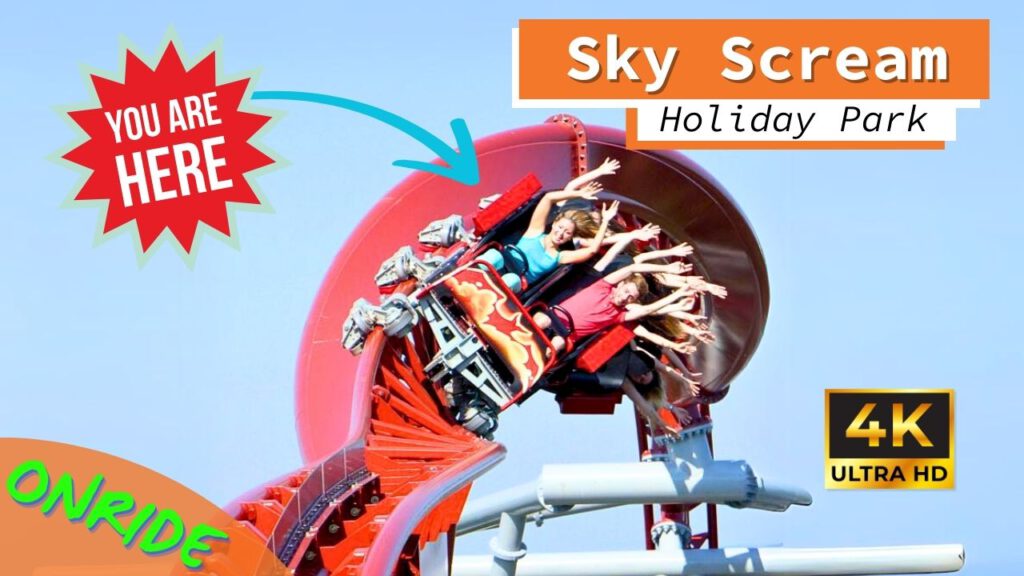 Eine Achterbahn mit dem Namen Sky Scream im Holiday Park führt Fahrgäste durch einen engen Looping. Die Insassen heben die Arme und wirken angespannt, während die Bahn eine kurvenreiche, steile Strecke entlangfährt. Im Hintergrund ist der blaue Himmel zu sehen, und im Bild befinden sich farbenfrohe Grafiken mit den Aufschriften "You are here", "Onride" und "4K Ultra HD".