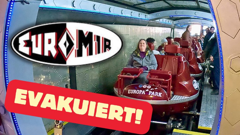 Stillstehender Euro-Mir-Zug im Europa-Park mit sitzenden und stehenden Fahrgästen, die auf eine Evakuierung warten. Schriftzug „Evakuiert!“ im Vordergrund.