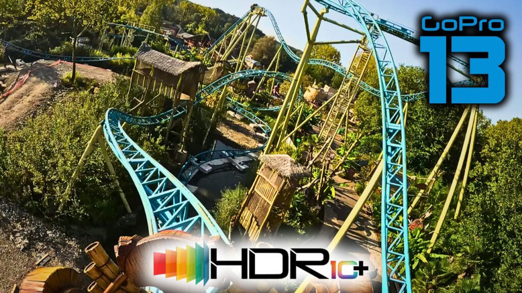 Die Tiki Waka Achterbahn im Freizeitpark Walibi Belgien, eine blaue Stahlachterbahn, schlängelt sich durch eine dschungelartige Landschaft mit tropischer Vegetation und hölzernen Hütten, festgehalten mit einer GoPro 13 Kamera in HDR10+.
