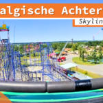 Blick auf die nostalgische Achterbahn im Skyline Park aus der Onride-Perspektive. Die Bahn besteht aus blauen Metallstrukturen und bietet steile Auf- und Abfahrten. Im Hintergrund sind weitere Attraktionen und die grüne Parklandschaft zu sehen. Ein "Skyline Park"-Schild sowie ein Hinweis auf die 4K Ultra HD-Qualität sind ebenfalls sichtbar.