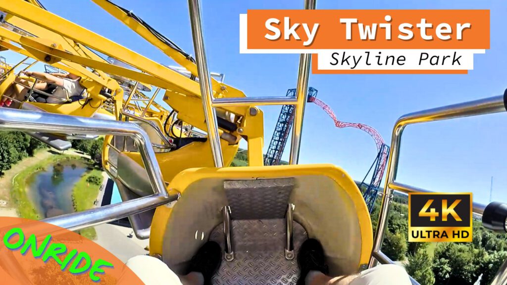 Blick aus der Onride-Perspektive auf die Attraktion Sky Twister im Skyline Park. Der gelbe Sitzbereich und Sicherheitsbügel sind im Vordergrund, während die Schiene und umliegende Landschaft sichtbar sind. Ein weiterer Fahrgast ist ebenfalls im Bild zu sehen. Auf dem Bild sind "4K Ultra HD" und "Onride" hervorgehoben.