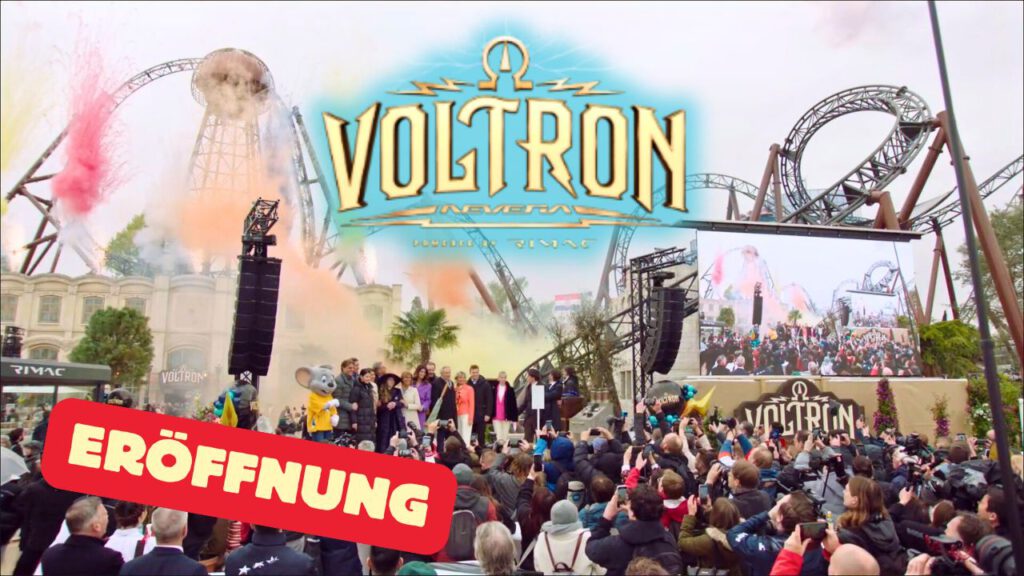 Presseevent zur Eröffnung der Achterbahn Voltron Nevera im Europa-Park. Eine große Menschenmenge versammelt sich vor einer Bühne, auf der mehrere Personen stehen. Im Hintergrund sind die verschlungenen Schienen der neuen Achterbahn sowie bunte Rauch- und Feuerwerkseffekte zu sehen. Auf einem großen Bildschirm wird die Bühne vergrößert dargestellt. Ein auffälliges Voltron Nevera-Logo dominiert das Bild.