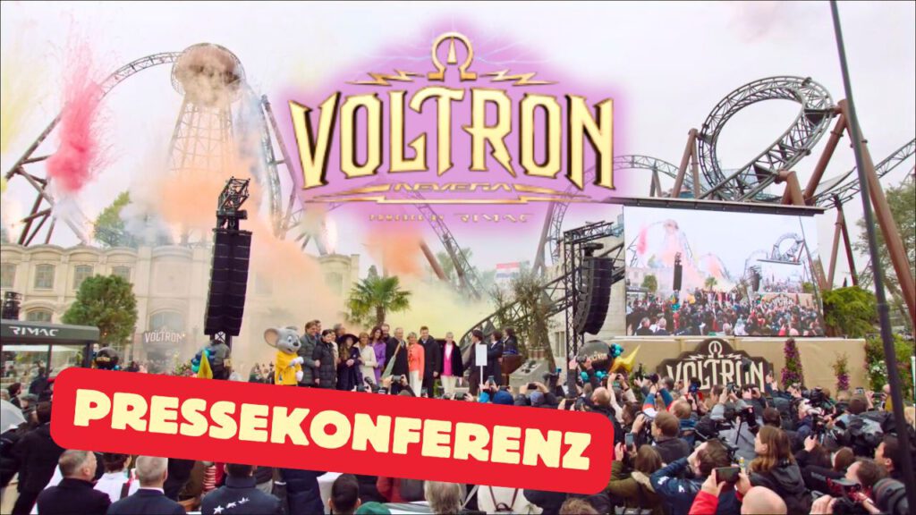 Bei der Pressekonferenz zur Eröffnung der neuen Achterbahn Voltron Nevera im Freizeitpark stehen mehrere Personen auf einer Bühne. Im Hintergrund sind die beeindruckenden Schienenkonstruktionen der Achterbahn zu sehen, begleitet von bunten Rauch- und Feuerwerkseffekten. Eine große Menschenmenge, darunter Journalisten und Fotografen, verfolgt das Ereignis. Auf einer Leinwand wird das Geschehen zusätzlich übertragen, während ein großes Voltron-Logo den Mittelpunkt des Bildes ziert.